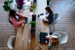 Women sitting together at an office table: how to create an office cleaning schedule