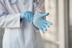 Healthcare professional putting on gloves.