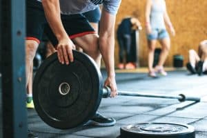 man putting plates on a barbell: your complete gym cleaning checklist