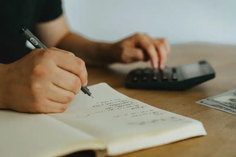 Man taking notes with a pen and notebook at his desk.