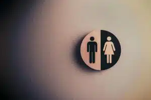 The exterior door of an office bathroom with a sign for both men and women