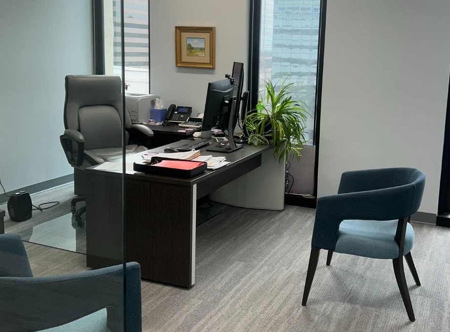 Professional office seating with two blue armchairs, a desk, and framed artwork